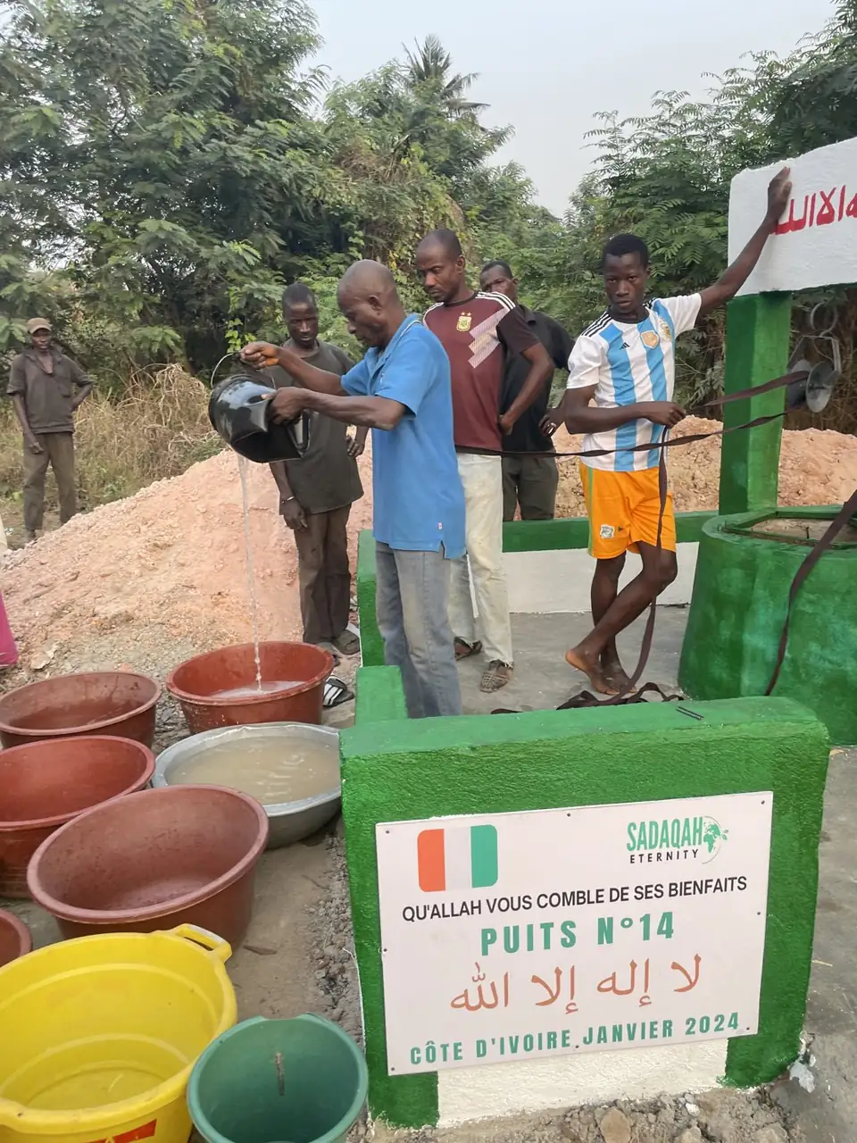 Des habitants remplissent leurs bassines au puits n°14, en Côte d'Ivoire