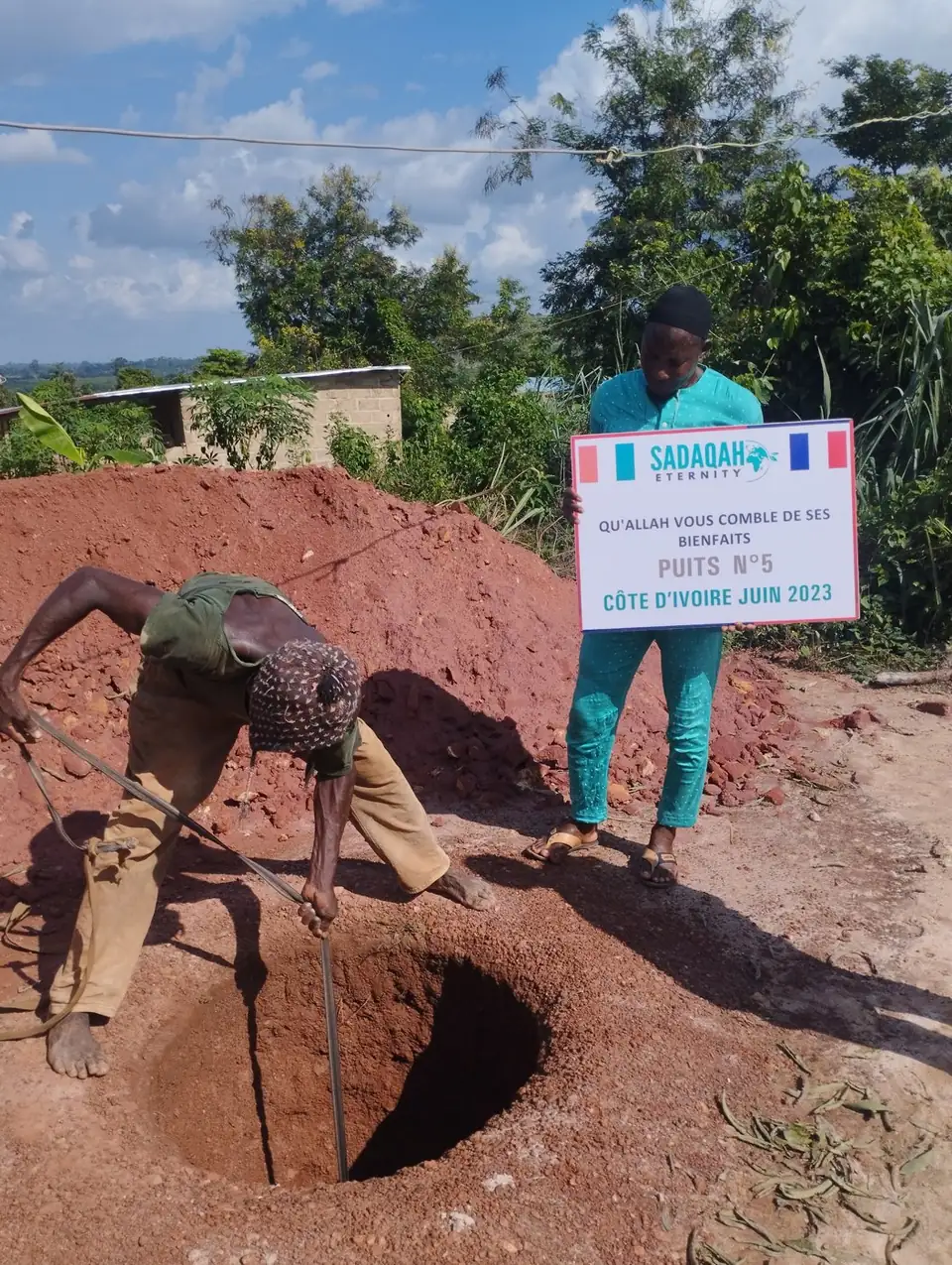 Un ouvrier creuse le puits à la main, à côté du panneau du chantier